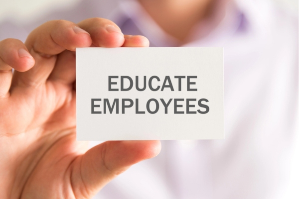 man holding a small card that says educate employees