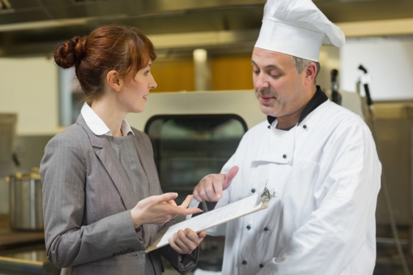 woman talking to a chef while holding a clipboard depicting evaluating propane use