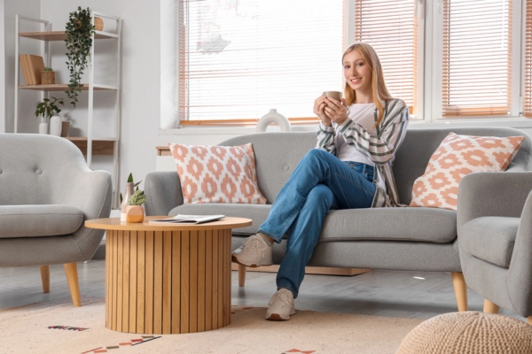 Young woman with cup of tea sitting on sofa depicting home comfort services