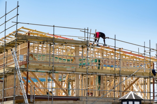 View of construction site with wooden frame and worker on top