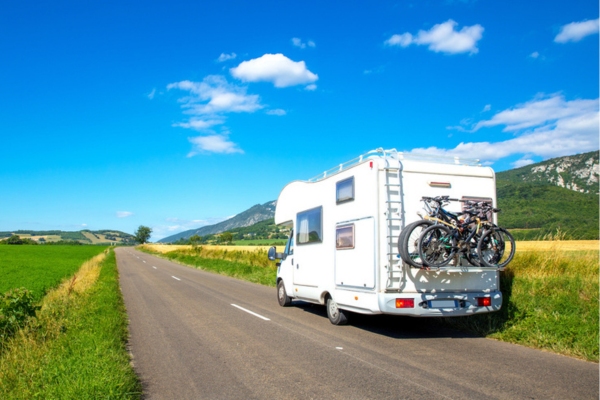 RV on the road with bikes for the family hanging on the back